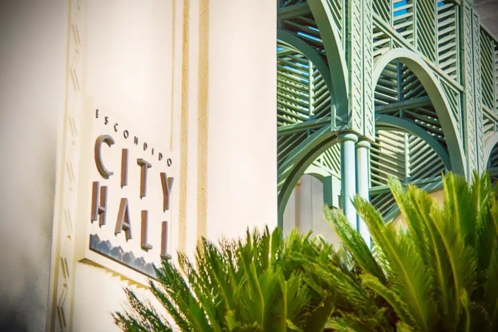 Close-up of a City of Escondido sign with palm trees and modern architectural details