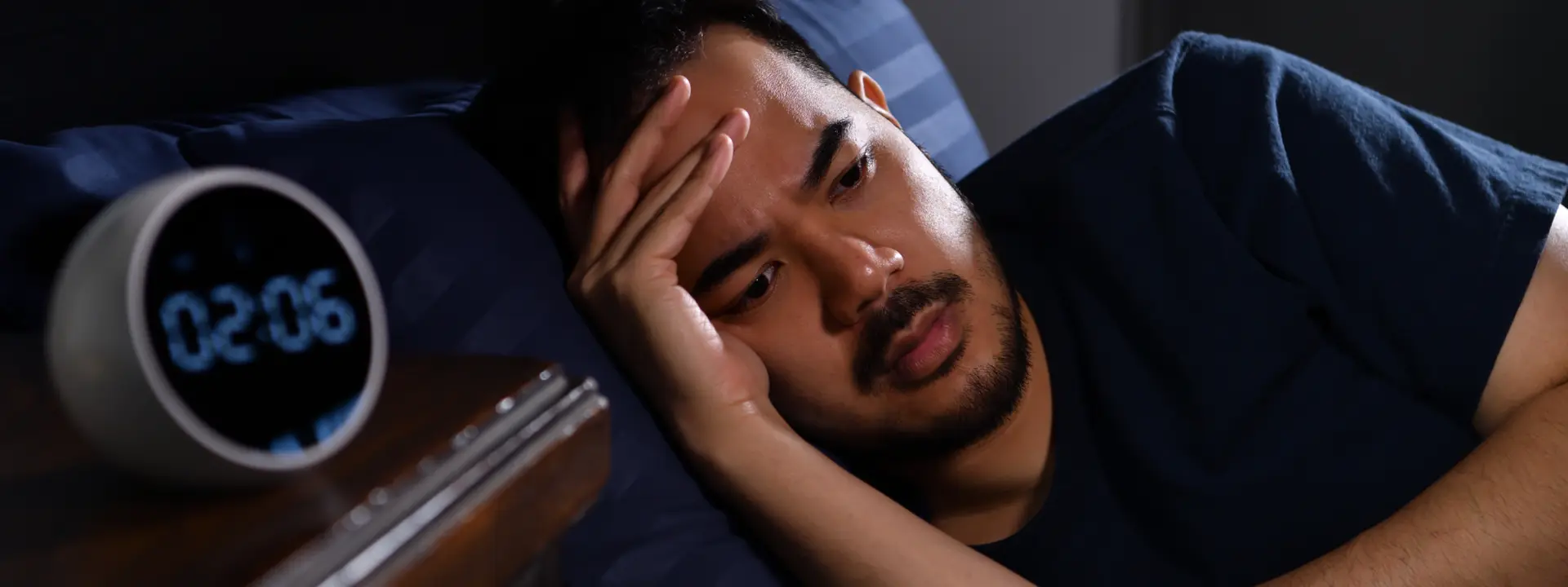 Individual checking the clock in the middle of the night showing insomnia frustration