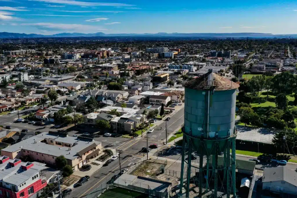 Aerial view of a city water tower surrounded by urban buildings and greenery.