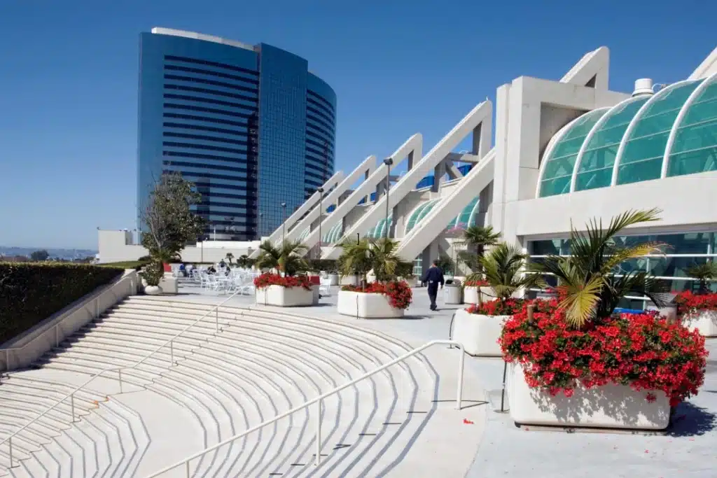 White steps ascend to a modern building entrance, framed by greenery on either side.